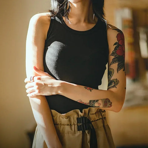 Person wearing a black sleeveless top with a heart design, standing indoors.